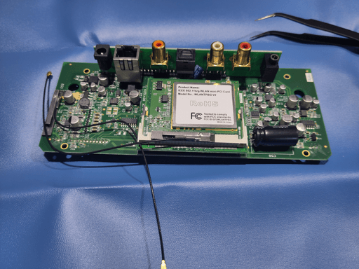 The motherboard of the squeezebox classic. It contains various small chips, capacitors and resistors. In center is a separate PCB housing the CPU with another PCB for wifi ontop. There's also another PCb that has sockets for digital and analogue audio, an ethernet jack and a power socket. That PCB is mounted at a right angle on the motherboard.