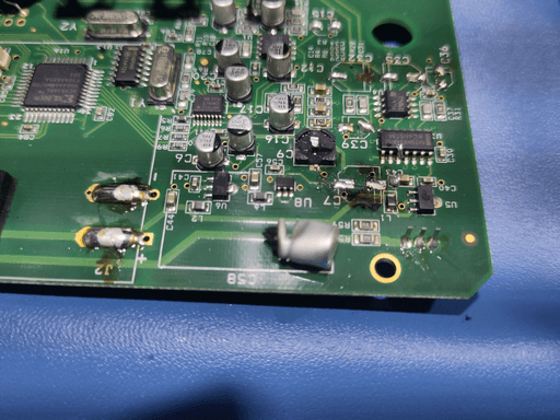 A photo of the motherboard with the cut-off part of a cap with the area it was cut away from in the background.