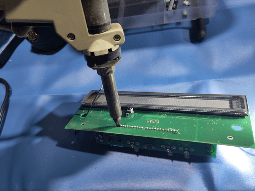 A desoldering gun on the front side of the motherboard, desoldering the pin headers that connect the board with all the outputs to the motherboard.