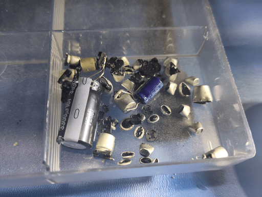 A small plastic box with various cut-apart capacitors.