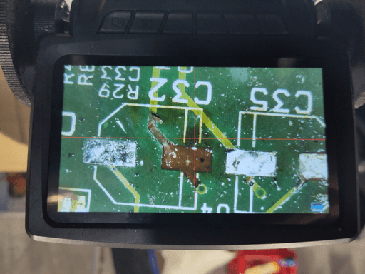 A photo of the screen of my microscope showing the ripped of pad where one of the capacitors was soldered to.