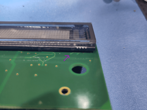 Another photo of the motherboard. This time on the front where a trace comes out from a via and directly disappears under the display. The trace is marked with a small arrow.