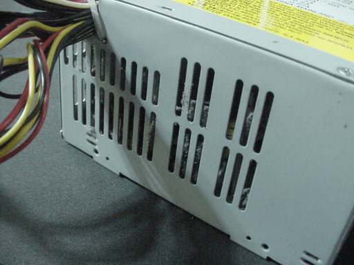 A photo looking into the air-holes on a power supply which is filled with lots of dust.