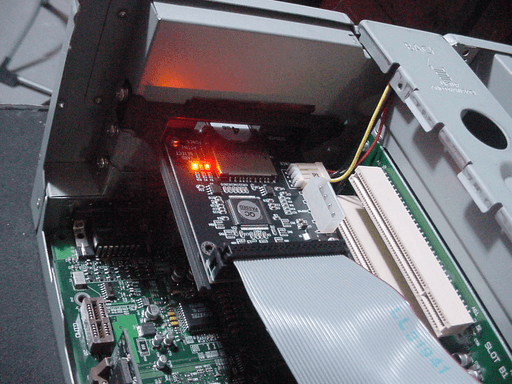 The IDE SD adapter in a black 3D printed bracket sitting on the back of a PC.