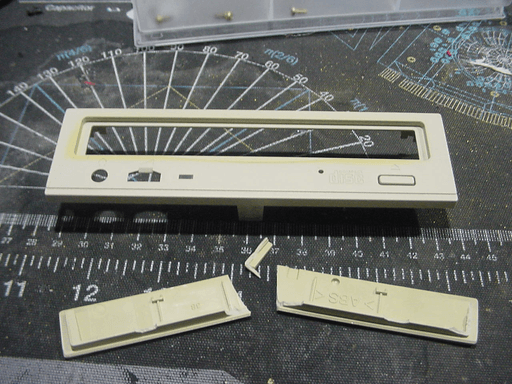 The decorative front of a cd drive tray broken in two.
