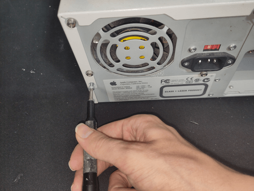 A photo of me using a beat up ifixit screwdriver to take out a screw on the back of a computer.