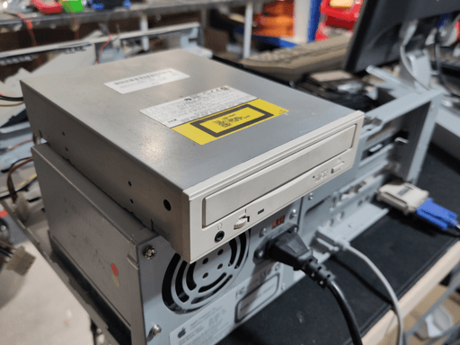 A beige CD drive sitting on a computer facing the back.