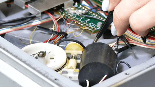 A photo of the motor-assembly that was missing the belt from a different angle. In the top right is my hand holding tweezers while I'm putting the belt in place.