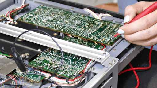 A picture of me measuring some solder-points on a PCB inside of the machine. The Ground-connection of the multimeter is connected to another PCB using a crocodile clamp.