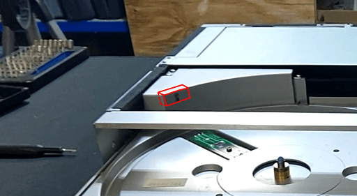 A picture of the record player with the top cover removed and the tray ejected. At the far back is a plastic-piece which is highlighted in red.