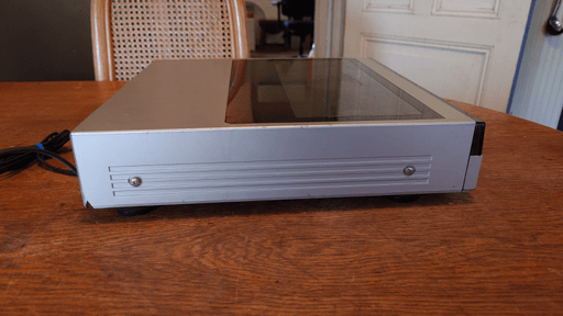 A side photo of the record player where a piece of the outer shell towards the back is missing.